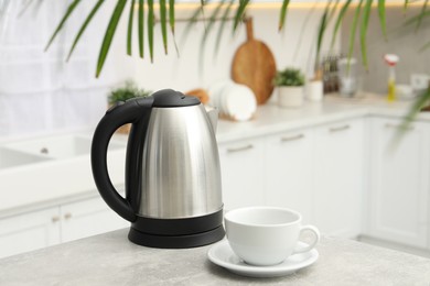 Photo of Electric kettle and cup on table in kitchen. Space for text