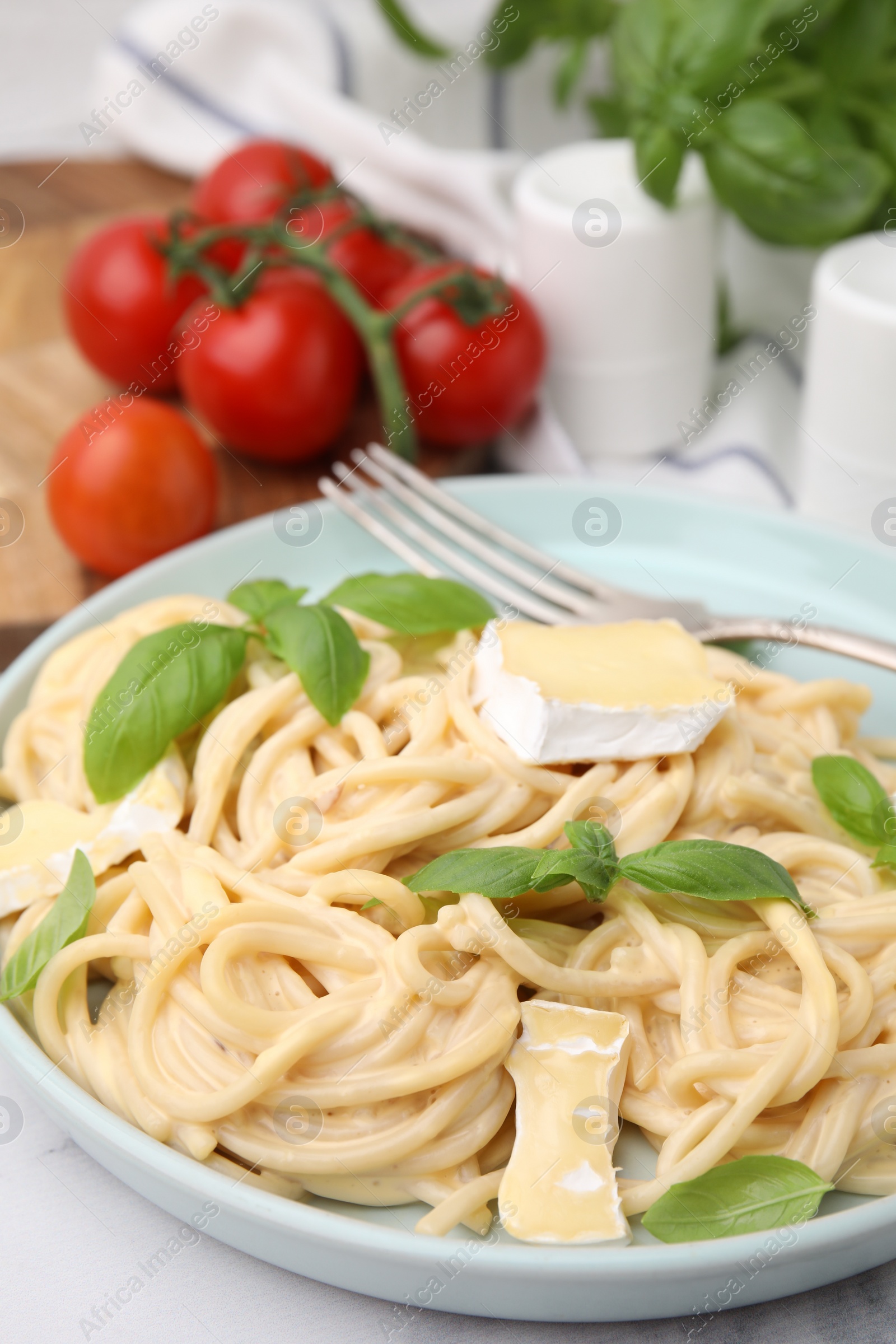 Photo of Delicious pasta with brie cheese and basil leaves on table, closeup