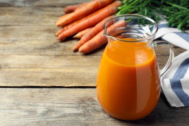 Photo of Healthy carrot juice on wooden table. Space for text