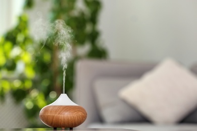 Photo of Aroma oil diffuser lamp on table against blurred background