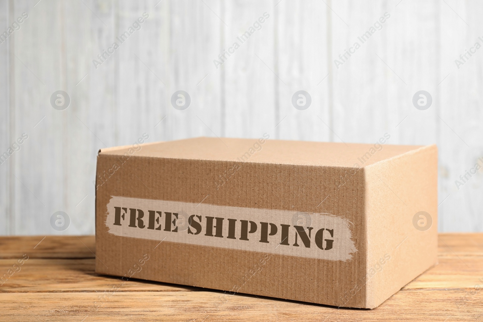 Image of Cardboard box on wooden table against white background. Free shipping