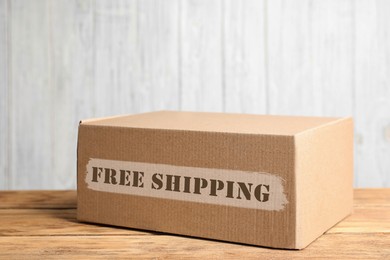 Image of Cardboard box on wooden table against white background. Free shipping