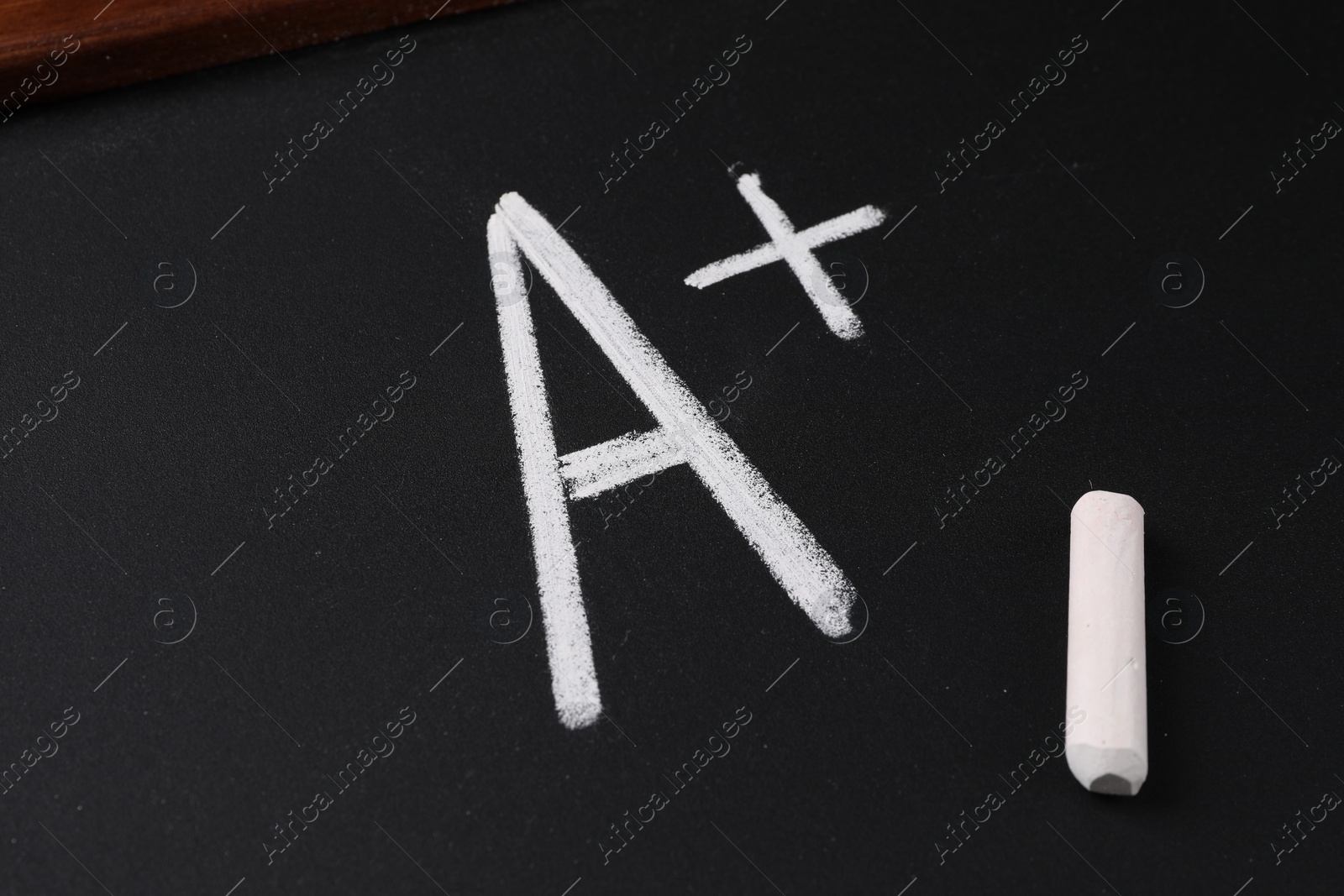 Photo of School grade. Letter A with plus symbol and chalk on blackboard, closeup