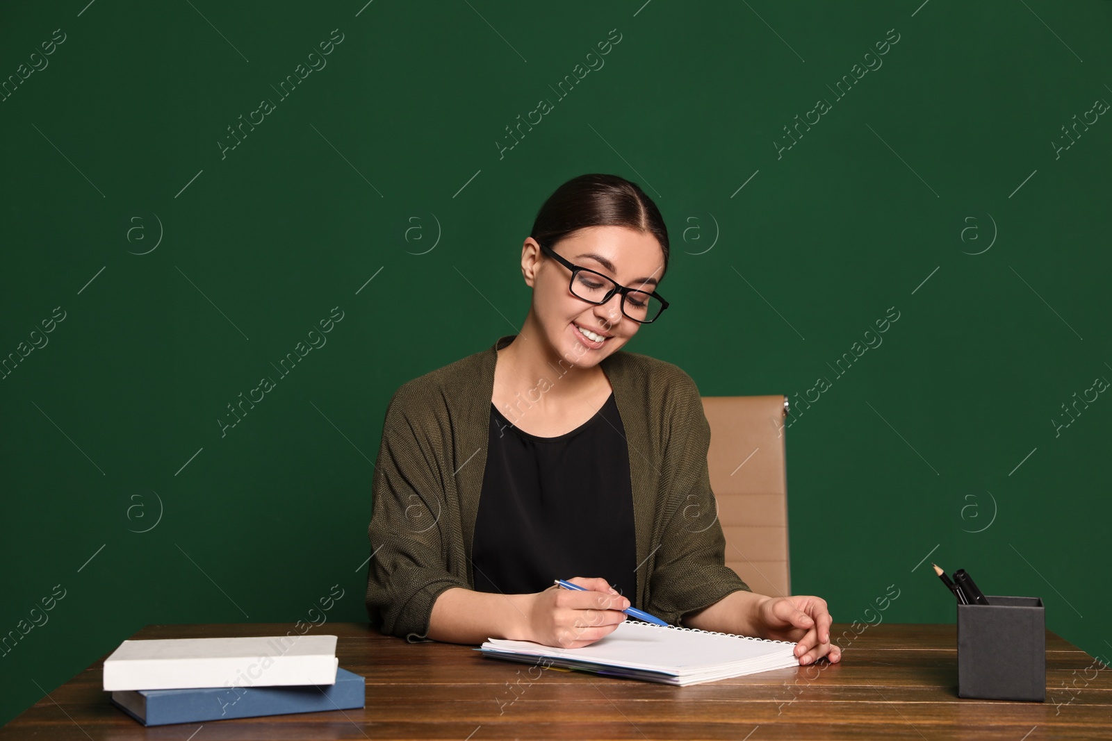 Photo of Portrait of young teacher at table against green background