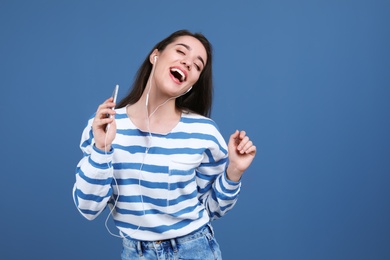 Photo of Young woman using phone for listening to music on color background