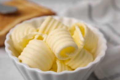 Photo of Tasty butter curls in bowl on table, closeup