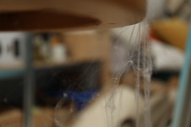 Photo of Old cobweb on table indoors, selective focus