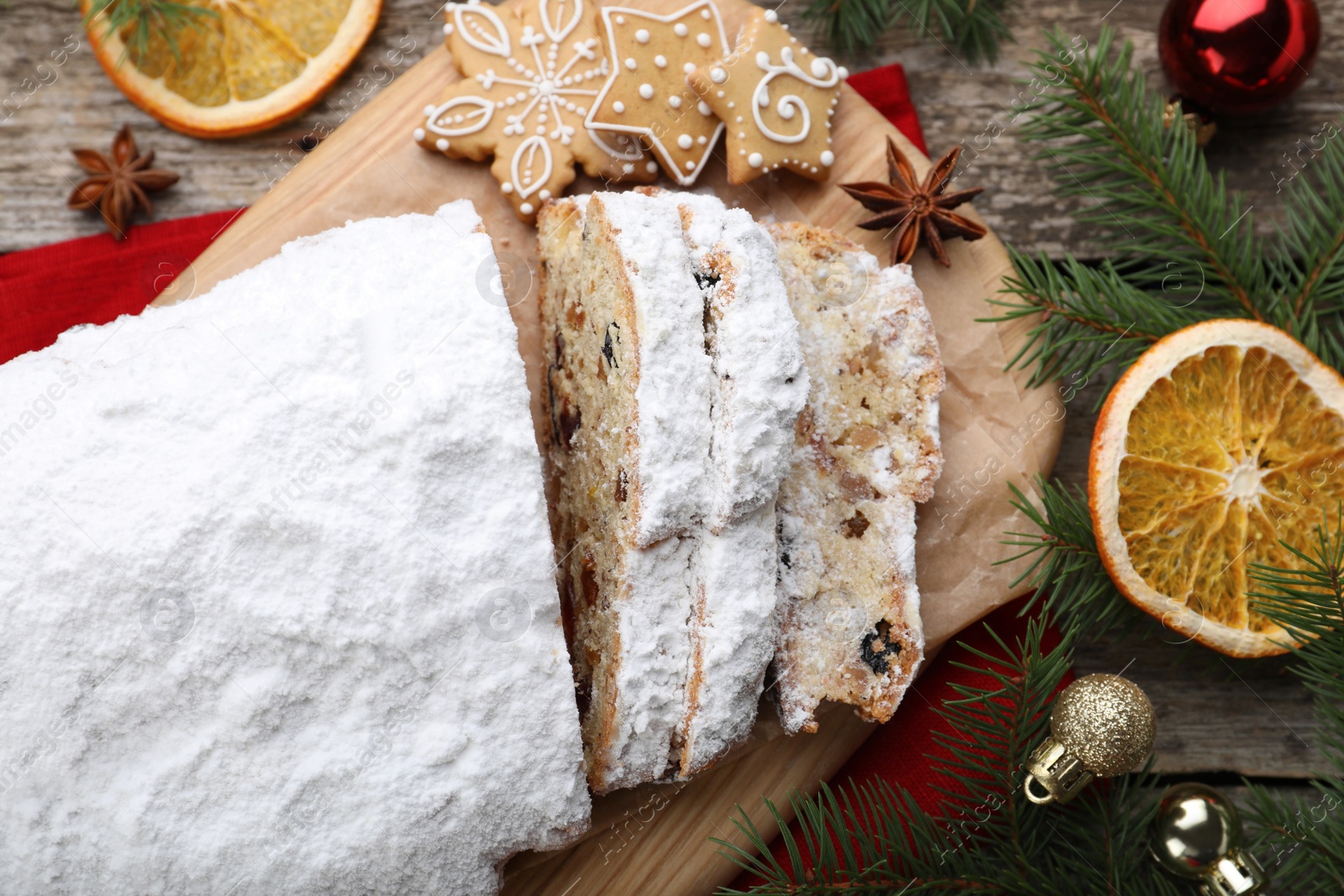 Photo of Traditional Christmas Stollen with icing sugar on wooden table, flat lay