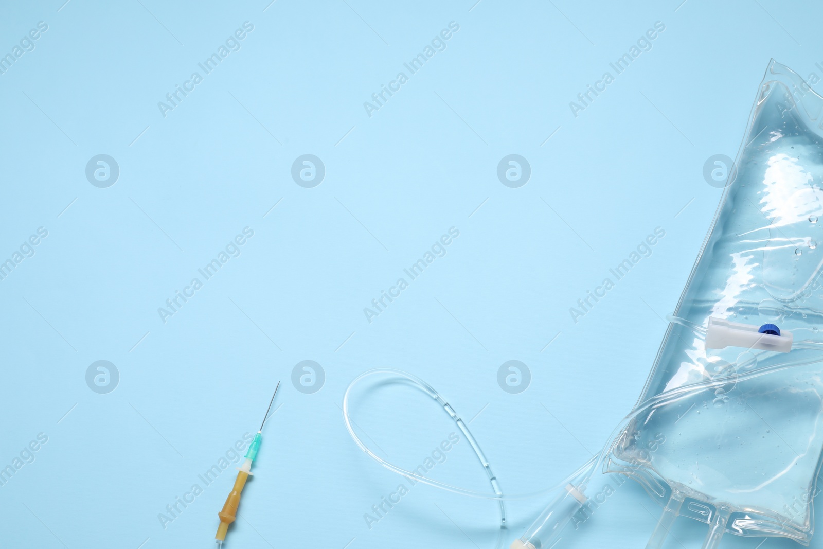 Photo of IV infusion set on light blue background, top view. Space for text