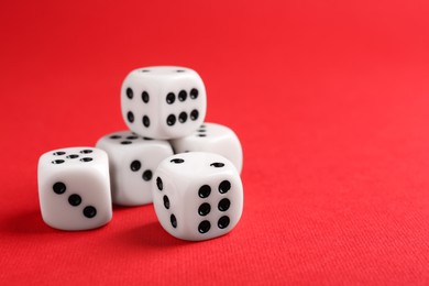 Photo of Many white game dices on red background, closeup. Space for text