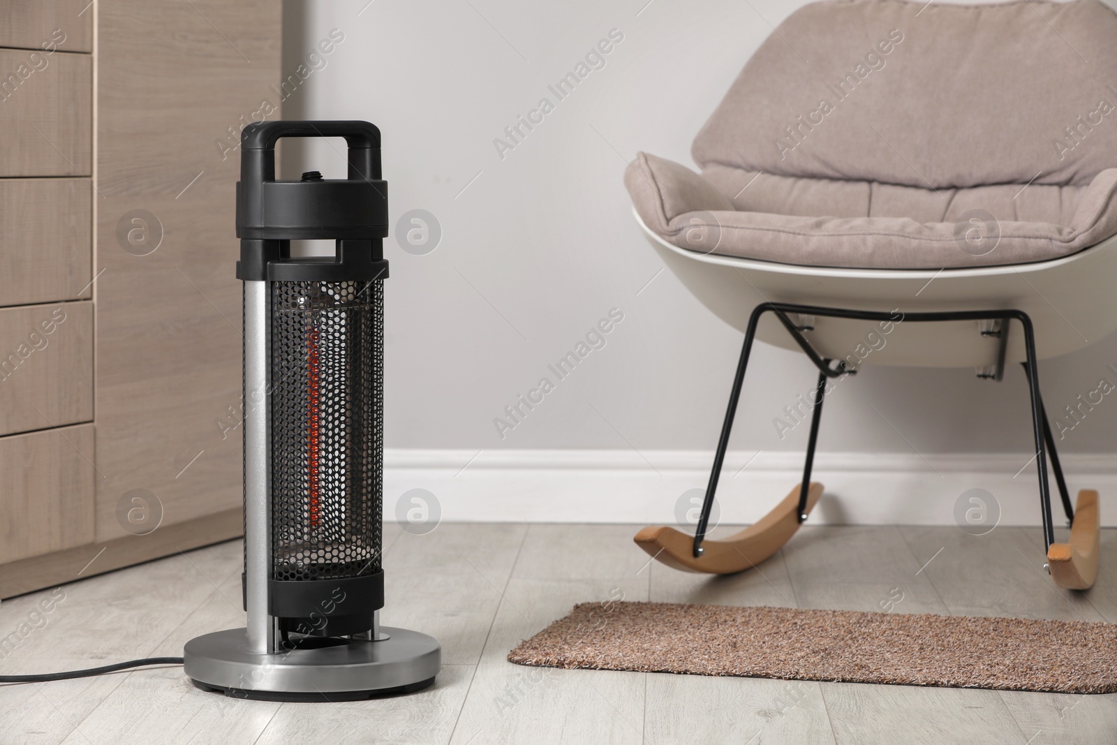 Photo of Modern infrared heater on floor in cozy room