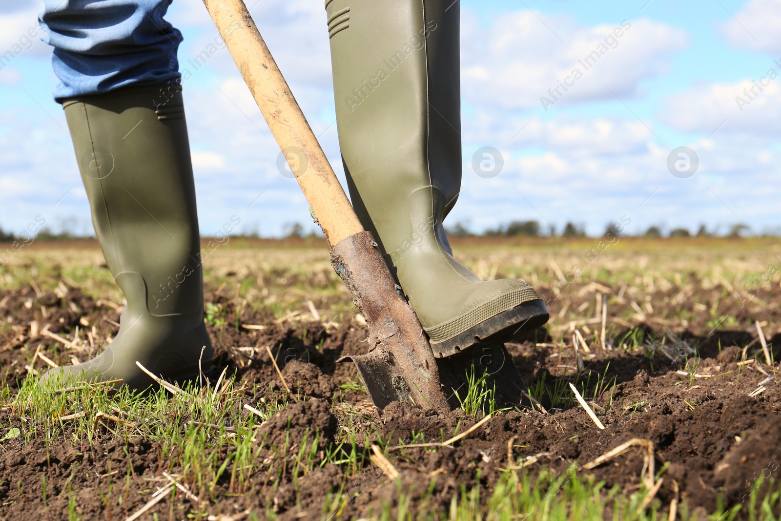 Photo of Man digging soil with shovel in field, closeup