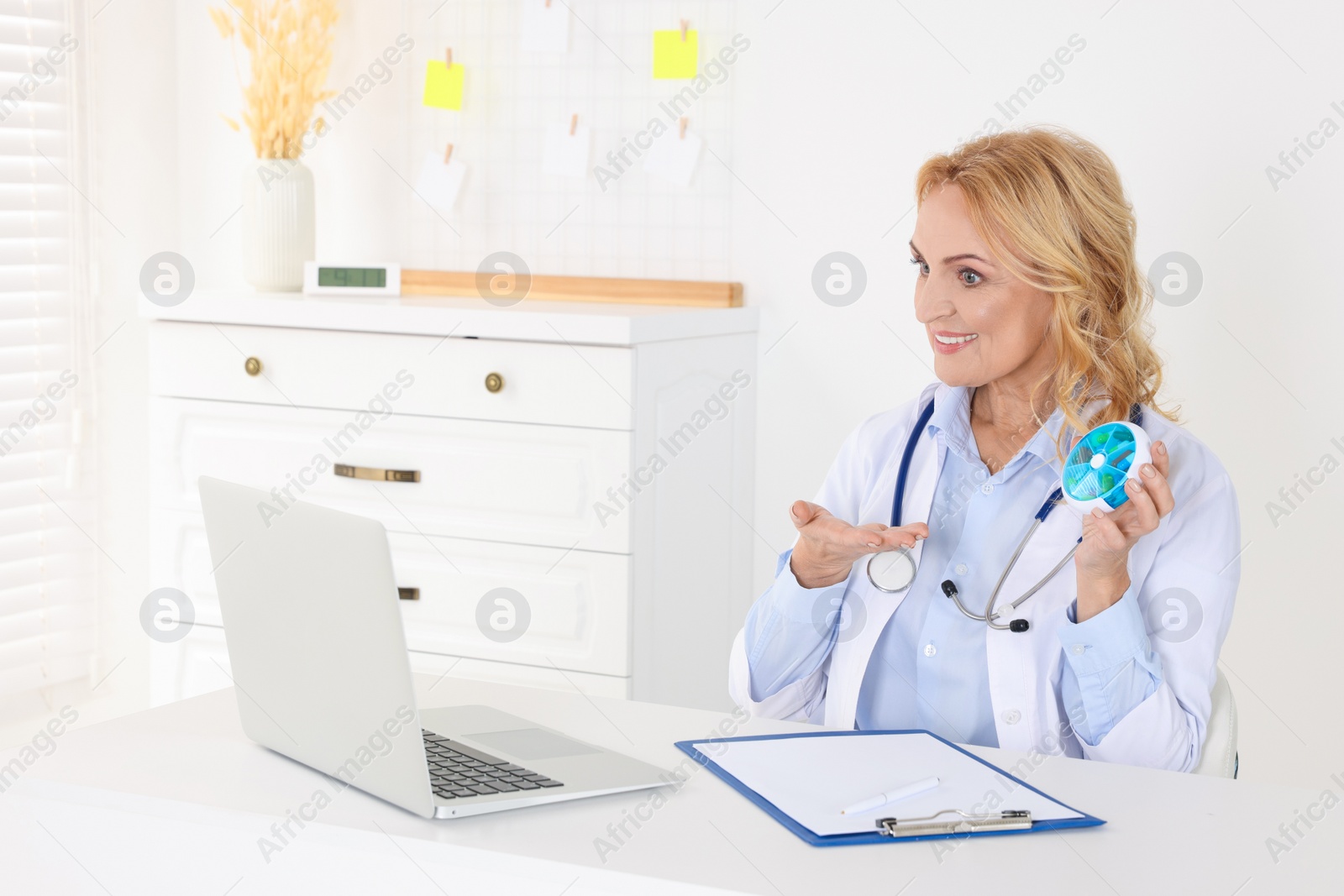 Photo of Doctor with laptop and pills consulting patient in clinic. Online medicine concept