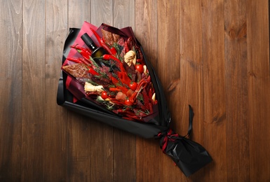 Beautiful edible bouquet with meat, cheese and vegetables on wooden table, top view