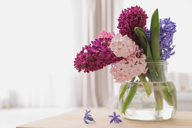 Photo of Beautiful hyacinths in glass vase on table indoors, space for text. Spring flowers