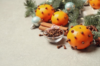 Photo of Delicious fresh tangerines with cloves on light table, space for text. Christmas celebration