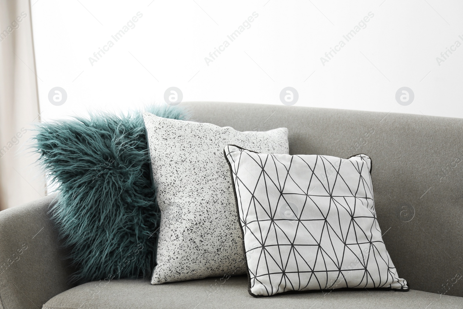 Photo of Different soft pillows on sofa in room. Interior element