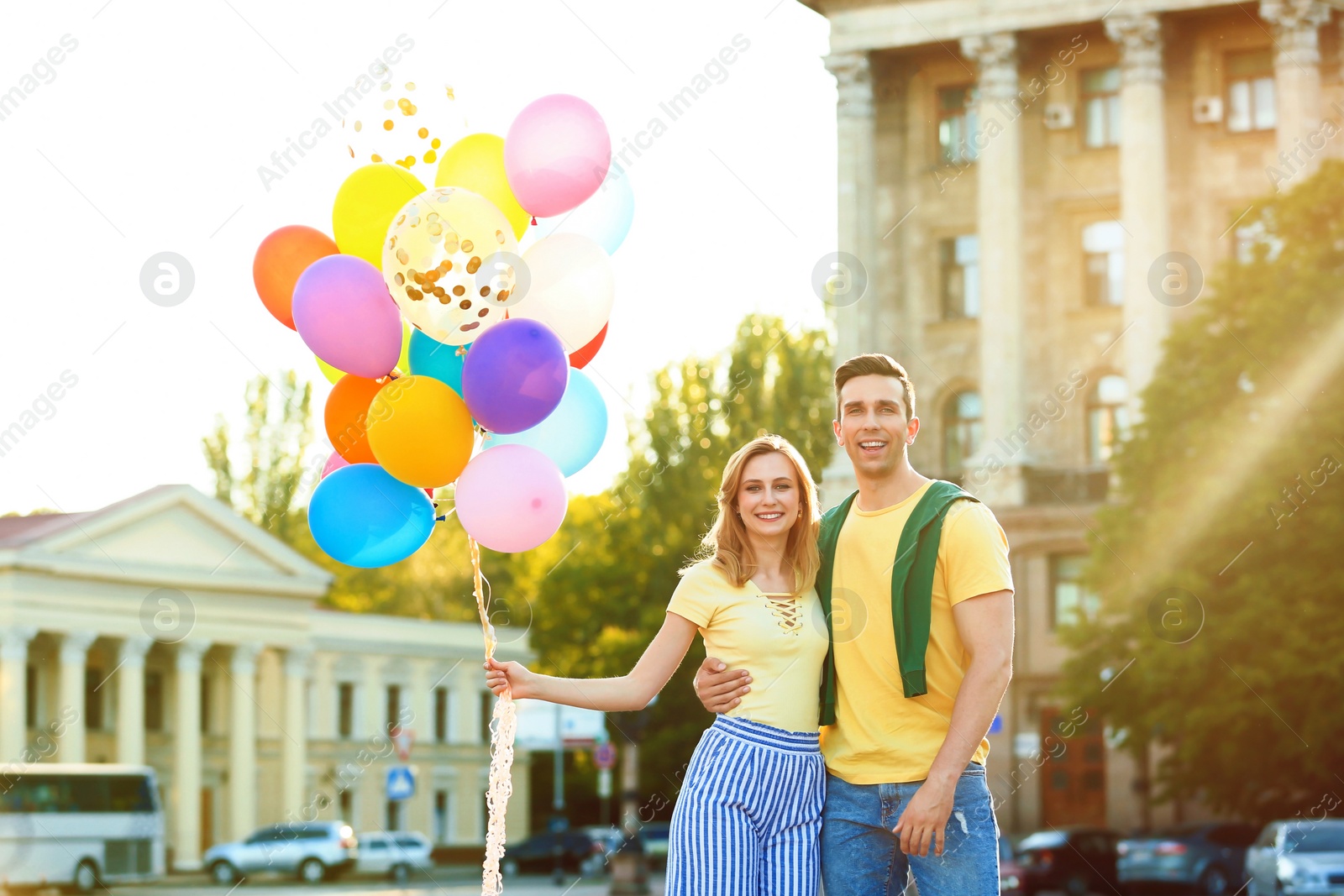 Photo of Young couple with colorful balloons outdoors on sunny day