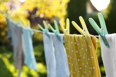 Photo of Clean clothes drying in garden, focus on clothespin