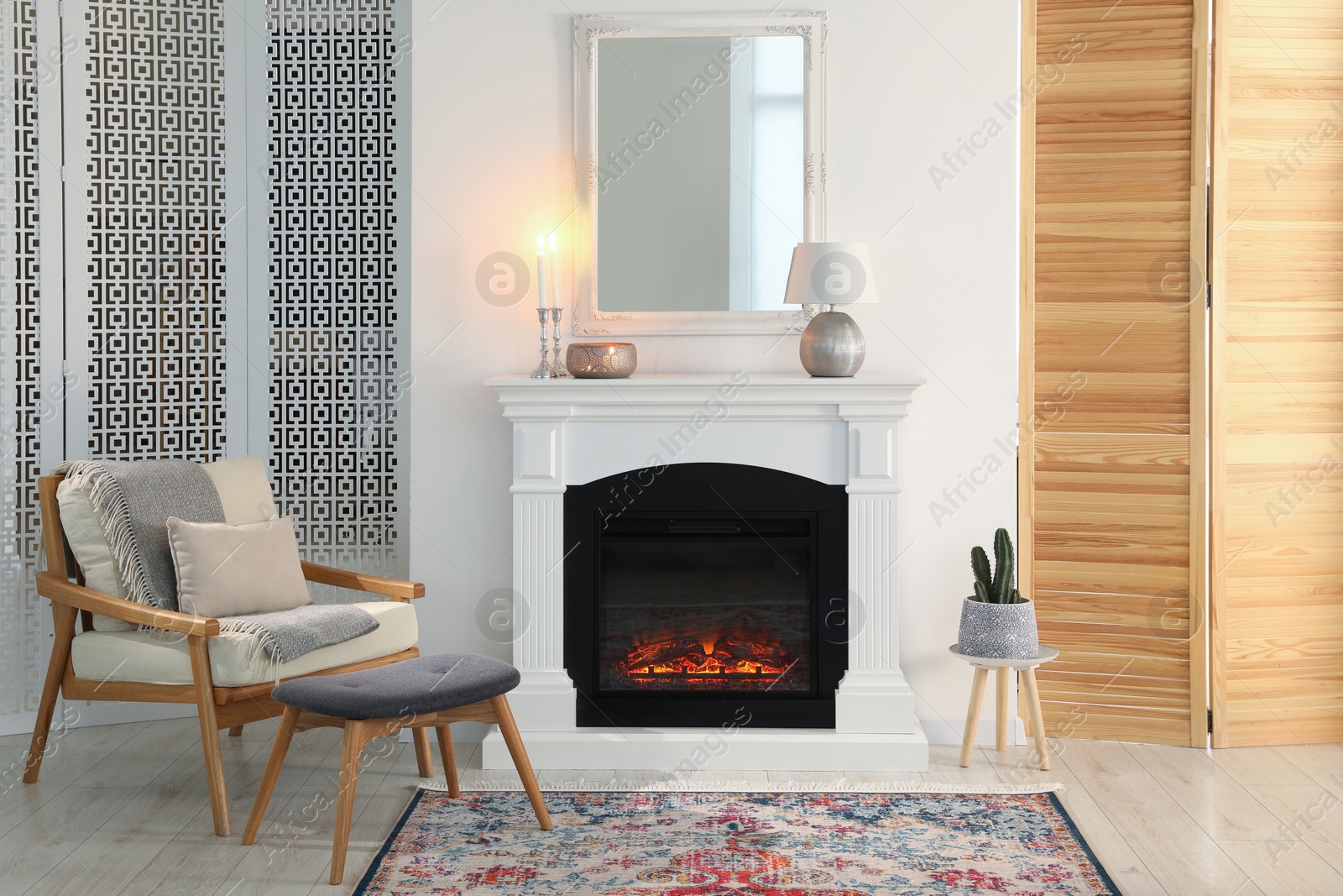 Photo of Beautiful fireplace, armchair and ottoman in living room. Interior design