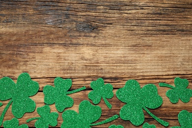 Photo of Flat lay composition with clover leaves on wooden background, space for text. St. Patrick's Day celebration