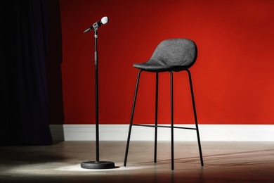 Microphone and stool on stage against color wall