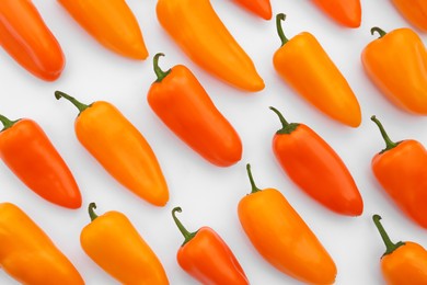 Photo of Many fresh raw orange hot chili peppers on white background, flat lay