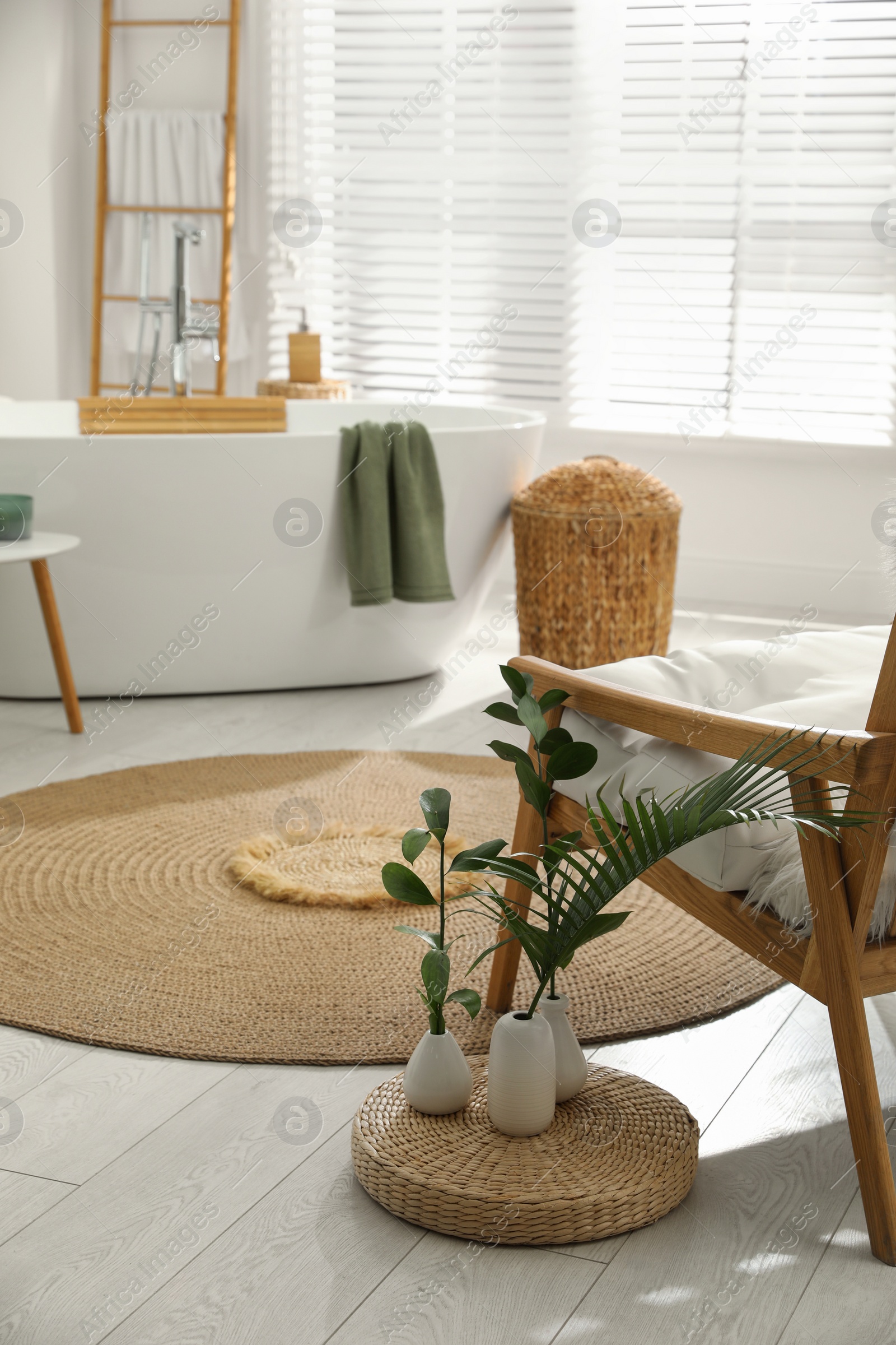 Photo of Comfortable armchair, green plants and mat in bathroom. Interior design