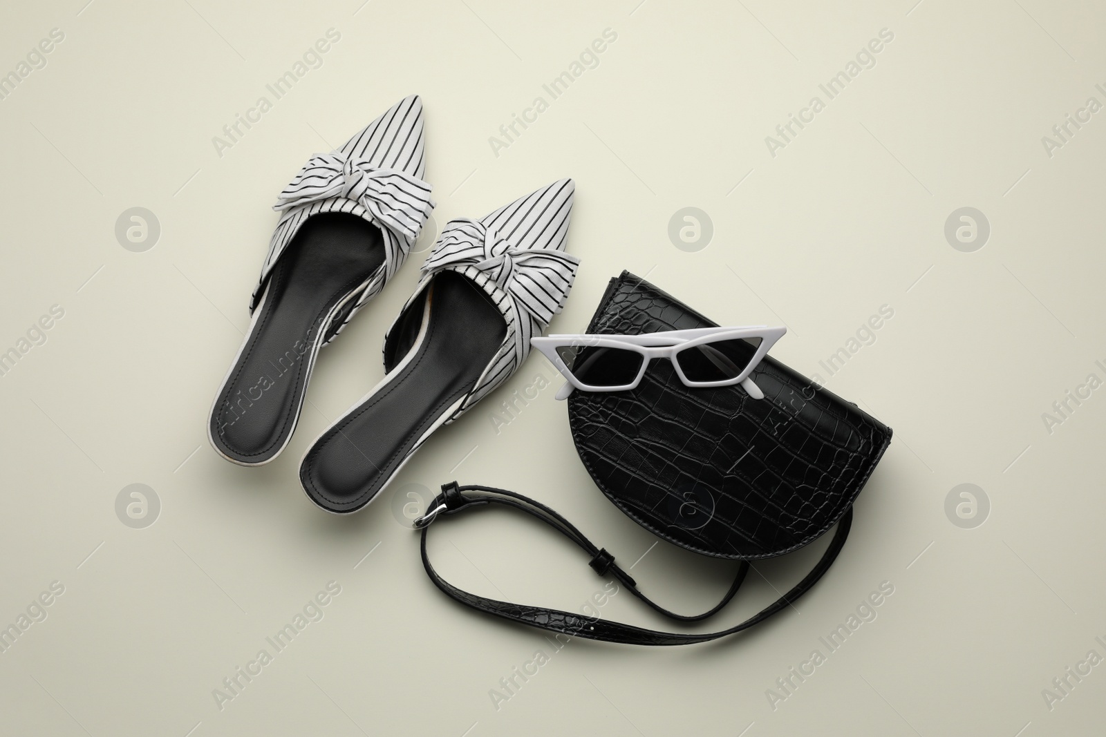 Photo of Stylish woman's bag, shoes and sunglasses on light background, flat lay