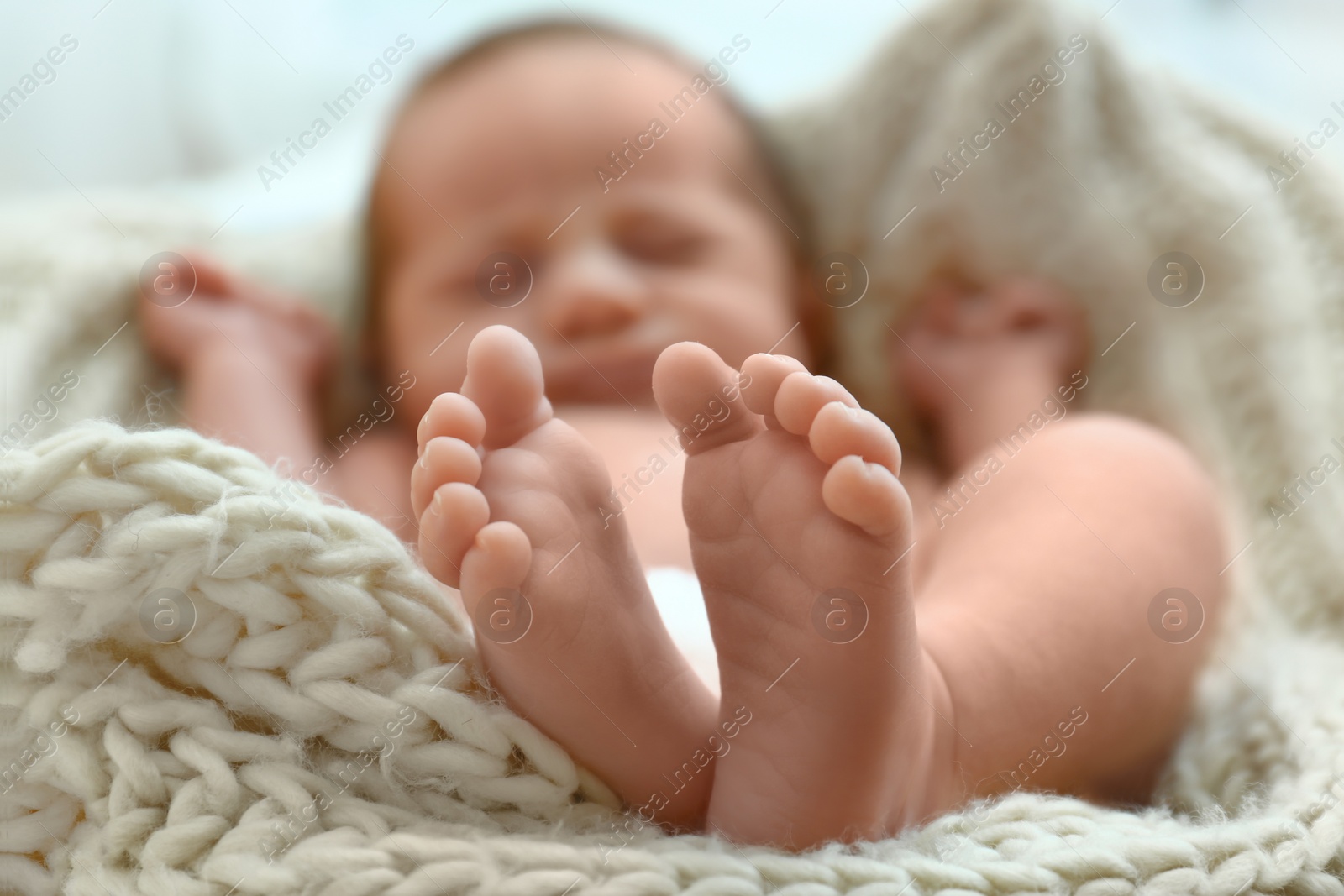 Photo of Cute little baby sleeping on knitted plaid in cradle, closeup
