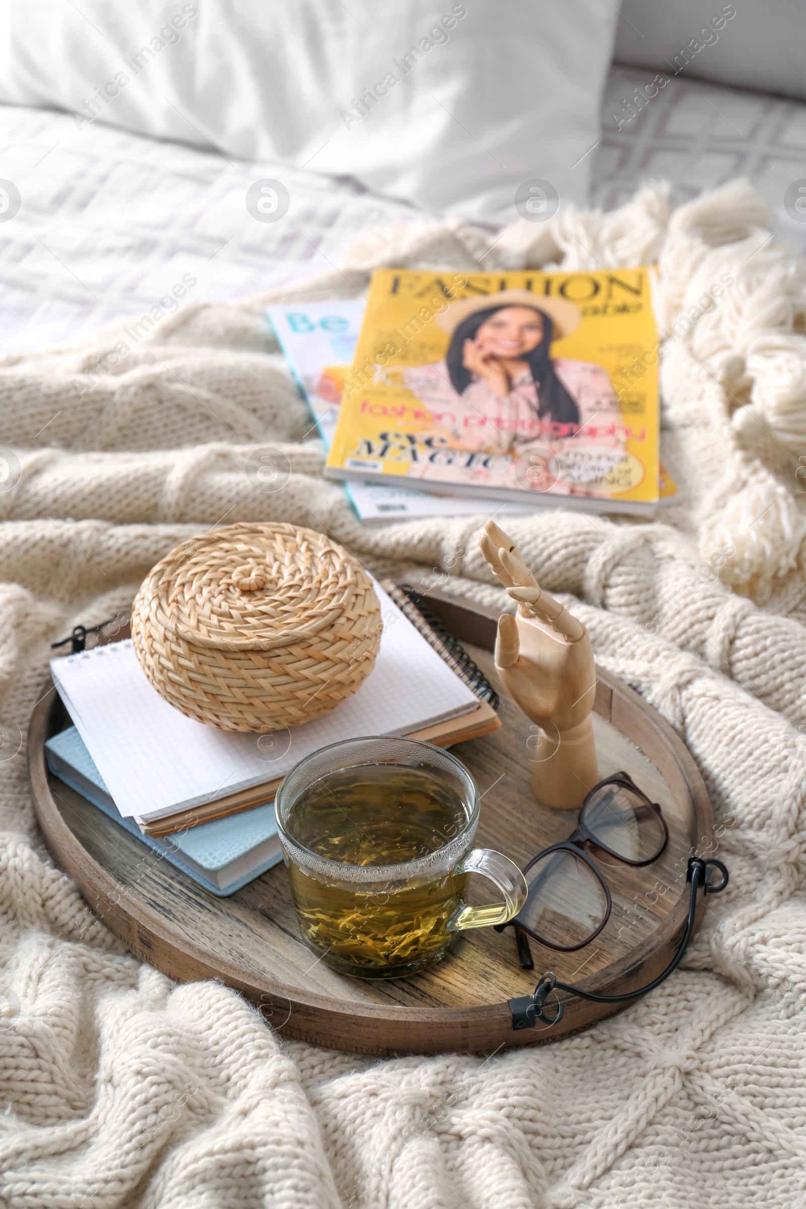 Photo of Stylish tray with different interior elements and tea on bed