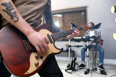 Photo of Man playing electric guitar during rehearsal in studio, closeup. Music band practice