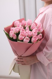 Woman with bouquet of beautiful fresh tulips on blurred background, closeup