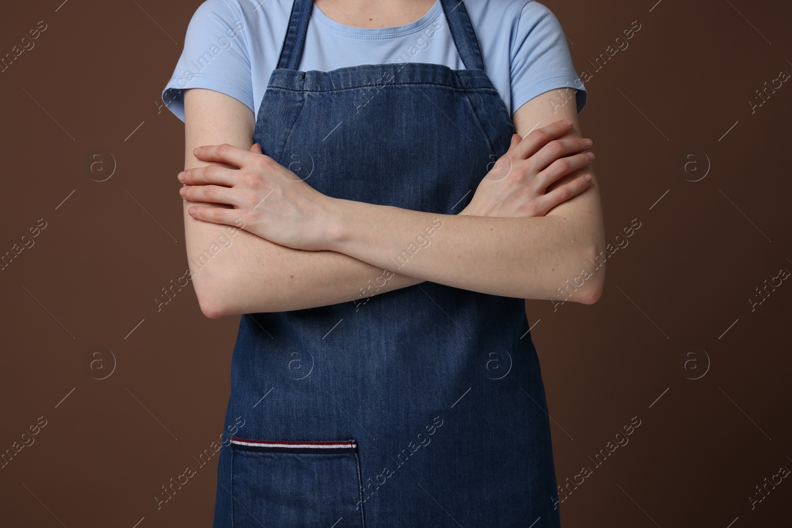 Photo of Woman wearing kitchen apron on brown background, closeup. Mockup for design