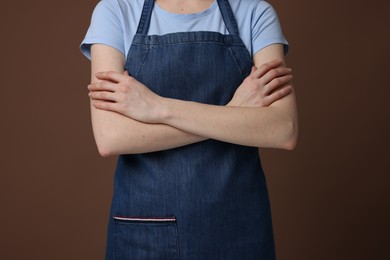 Photo of Woman wearing kitchen apron on brown background, closeup. Mockup for design