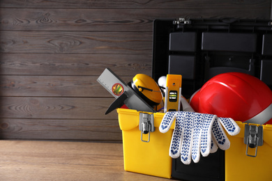 Plastic box with construction tools on wooden table. Space for text