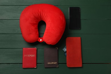 Photo of Flat lay composition with red travel pillow and smartphone on green wooden background