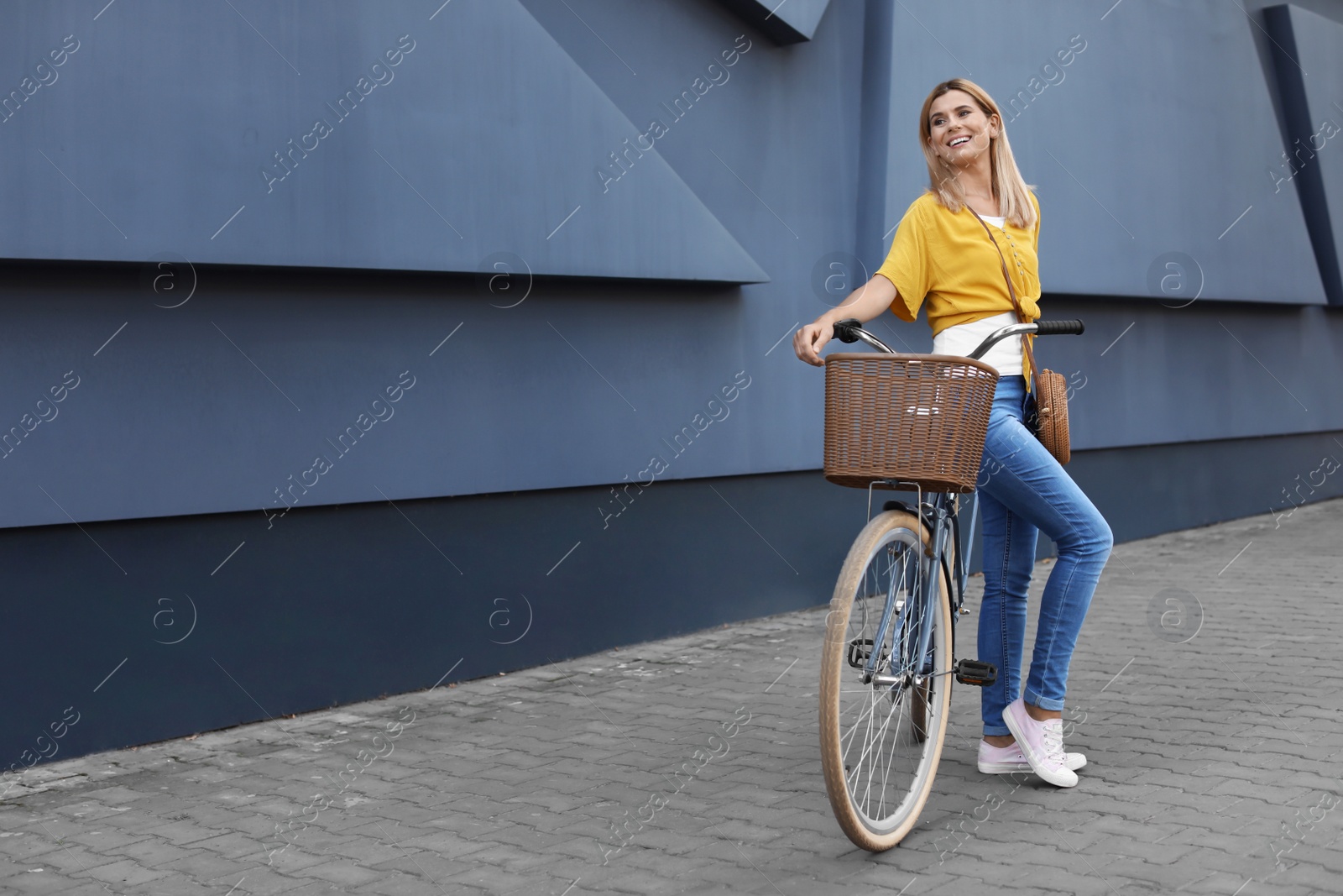 Photo of Woman with bicycle on street near gray wall