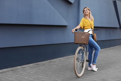 Photo of Woman with bicycle on street near gray wall