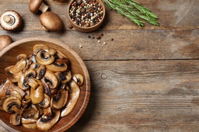 Photo of Flat lay composition with plate of fried mushrooms and space for text on wooden background