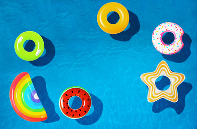 Image of Different inflatable rings floating in swimming pool, top view