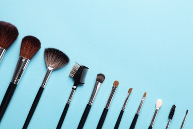 Photo of Set of makeup brushes on light blue background, flat lay. Space for text