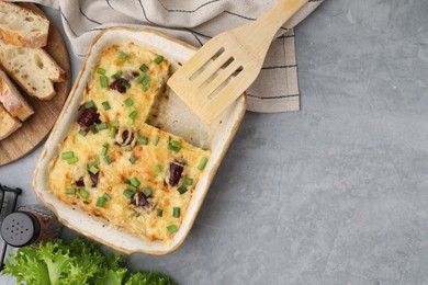 Photo of Tasty sausage casserole with green onions served on grey table, flat lay. Space for text