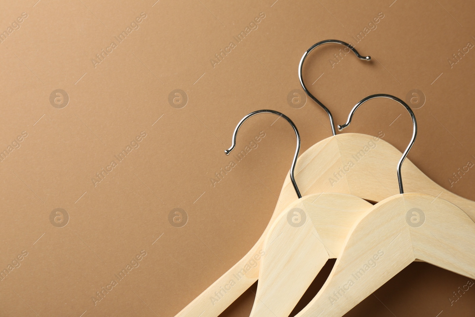 Photo of Wooden hangers on brown background, top view. Space for text