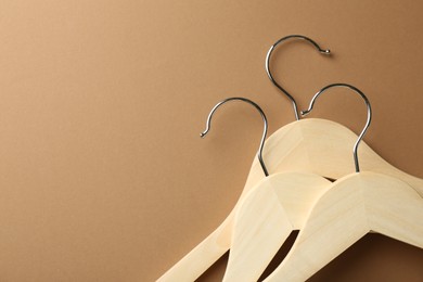 Wooden hangers on brown background, top view. Space for text
