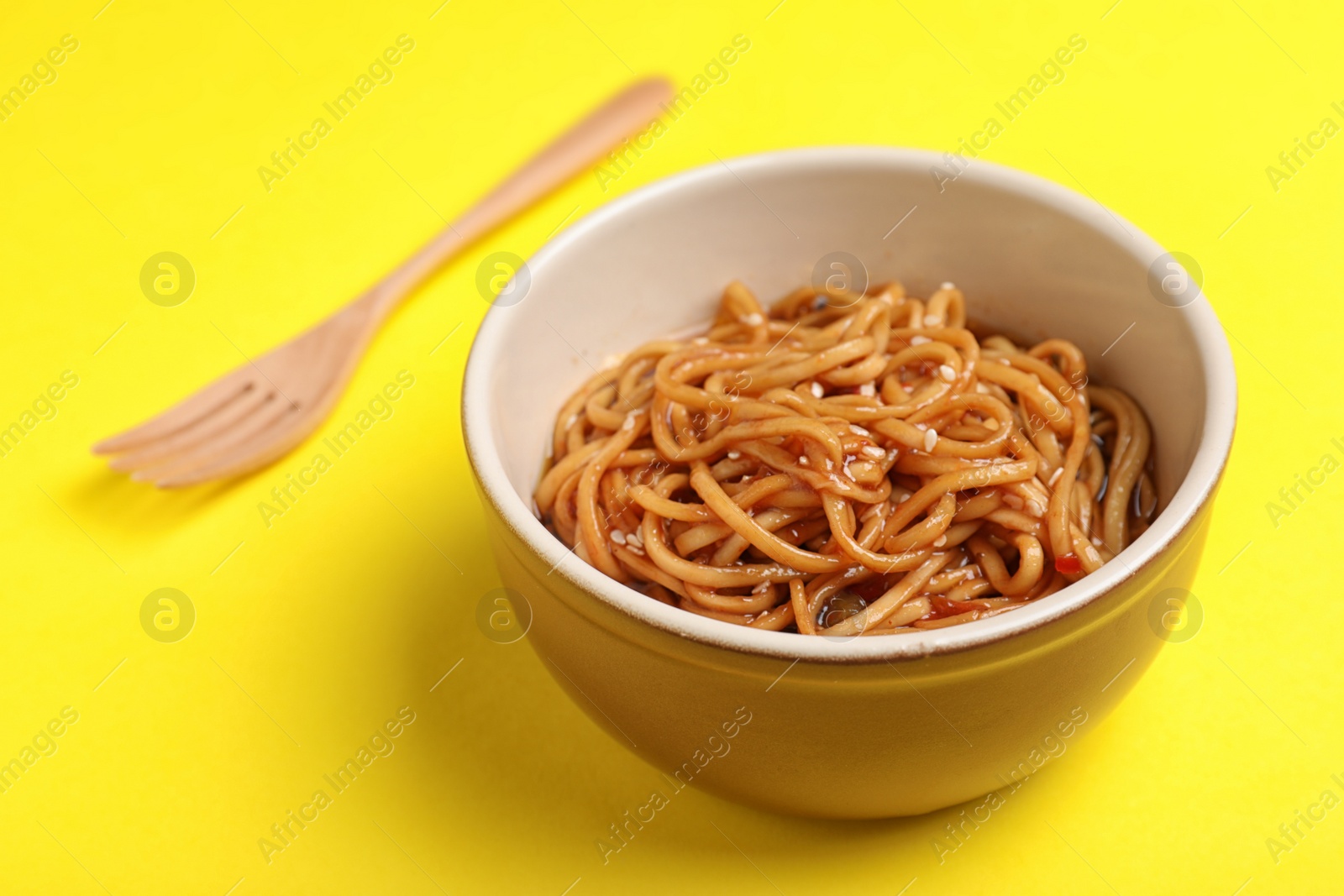 Photo of Cooked noodles and wooden fork on yellow background