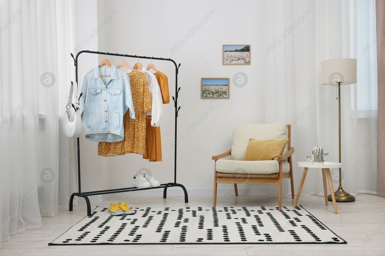 Photo of Stylish showroom interior with clothing rack and armchair