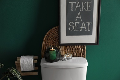 Photo of Decor elements, paper roll and toilet bowl near green wall. Bathroom interior