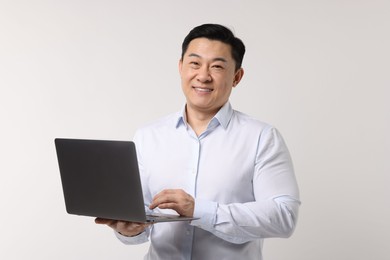 Portrait of happy man with laptop on light background