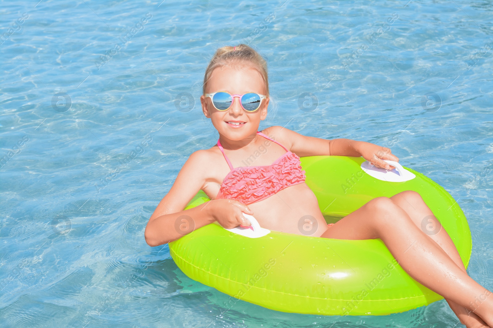 Photo of Happy little girl with inflatable ring in sea on sunny day